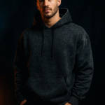 Man wearing a black acid wash hoodie with hands in pockets, embodying sleek and edgy streetwear fashion.