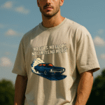 Man wearing an off-white oversized t-shirt featuring a vintage muscle car burnout graphic and the bold quote “No Guts, No Glory. No Limits, No Mercy” printed on the front, standing outdoors under a clear blue sky.